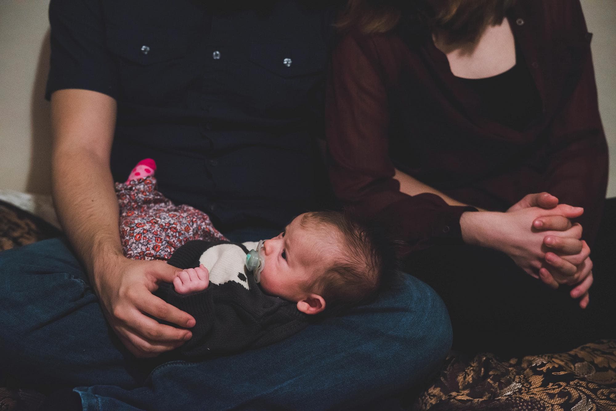 Mom and dad with newborn holding hands lifestyle session