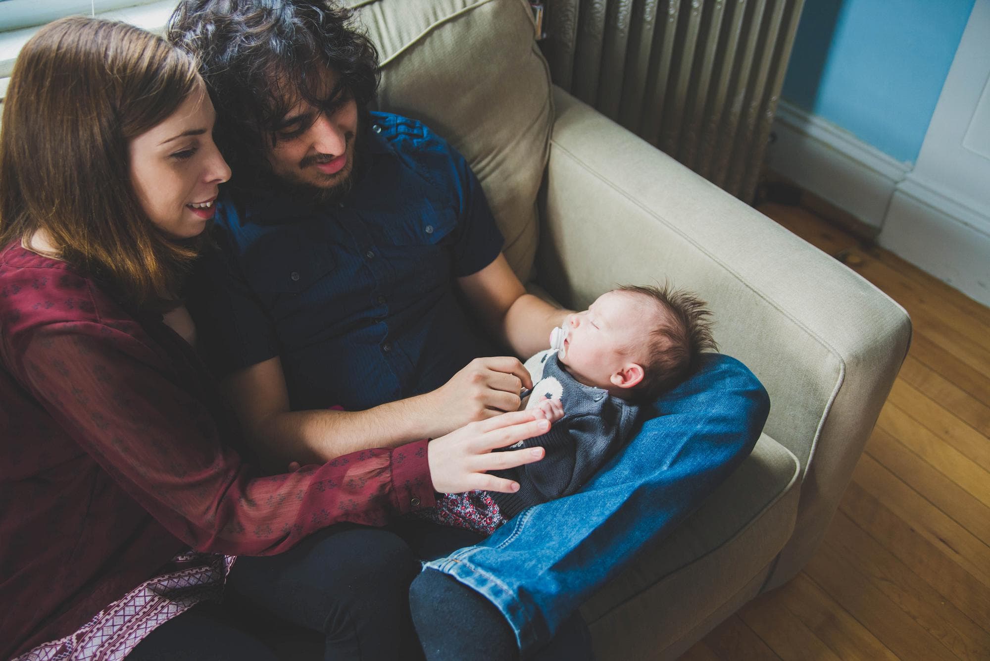 Mom and dad with newborn on lap on couch lifestyle session
