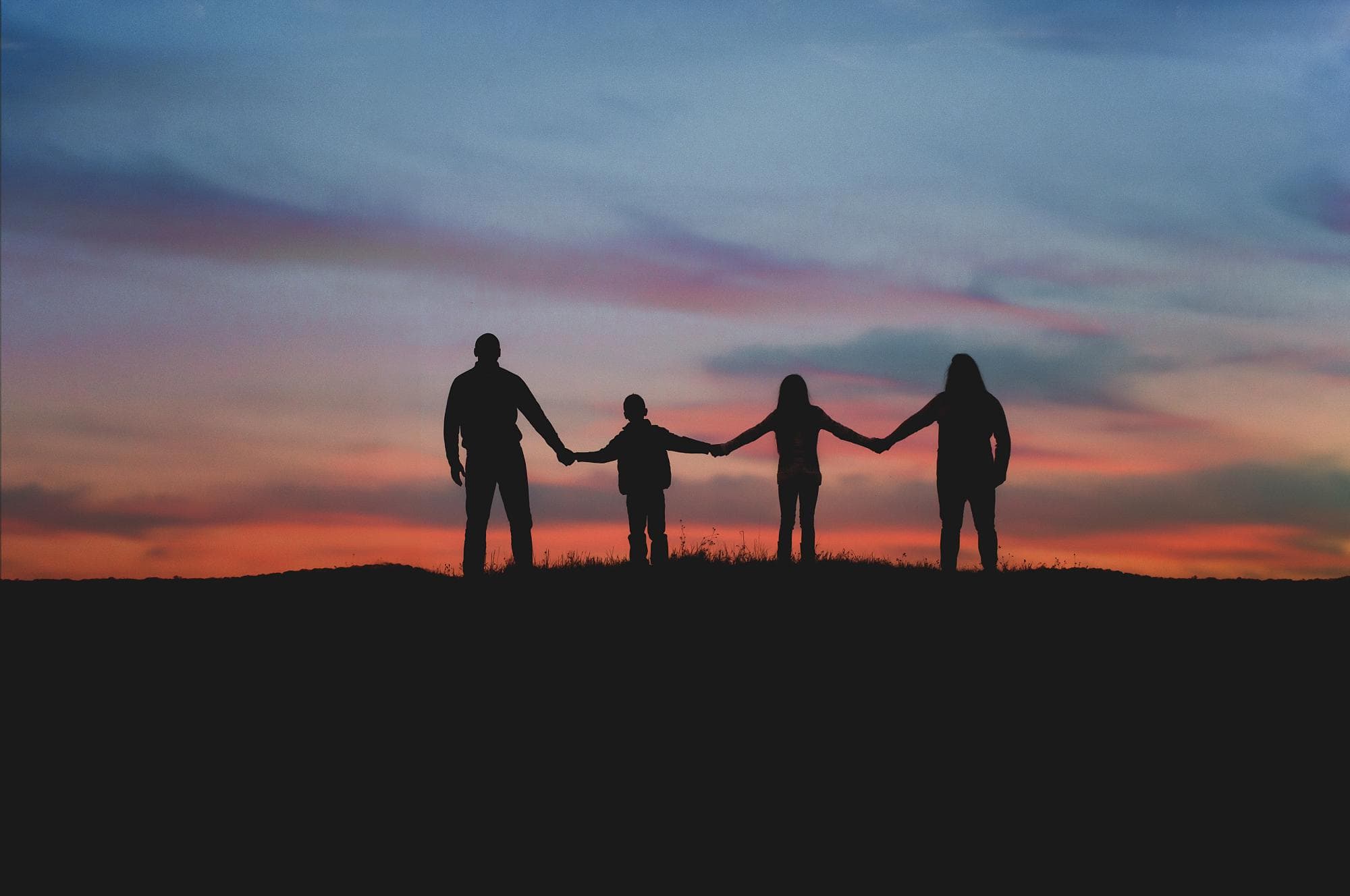 family-four-holding-hands-silhouette-sunset