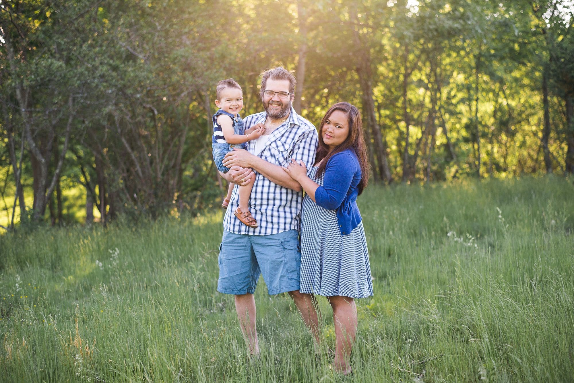 Family portrait session outdoors with golden sunlight behind them