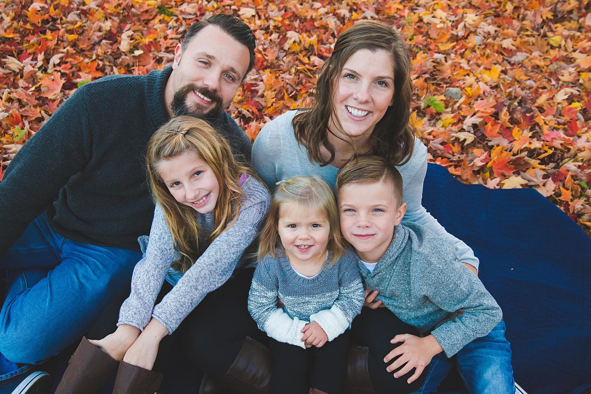 Family of 5 on a blanket in the Fall looking at the camera