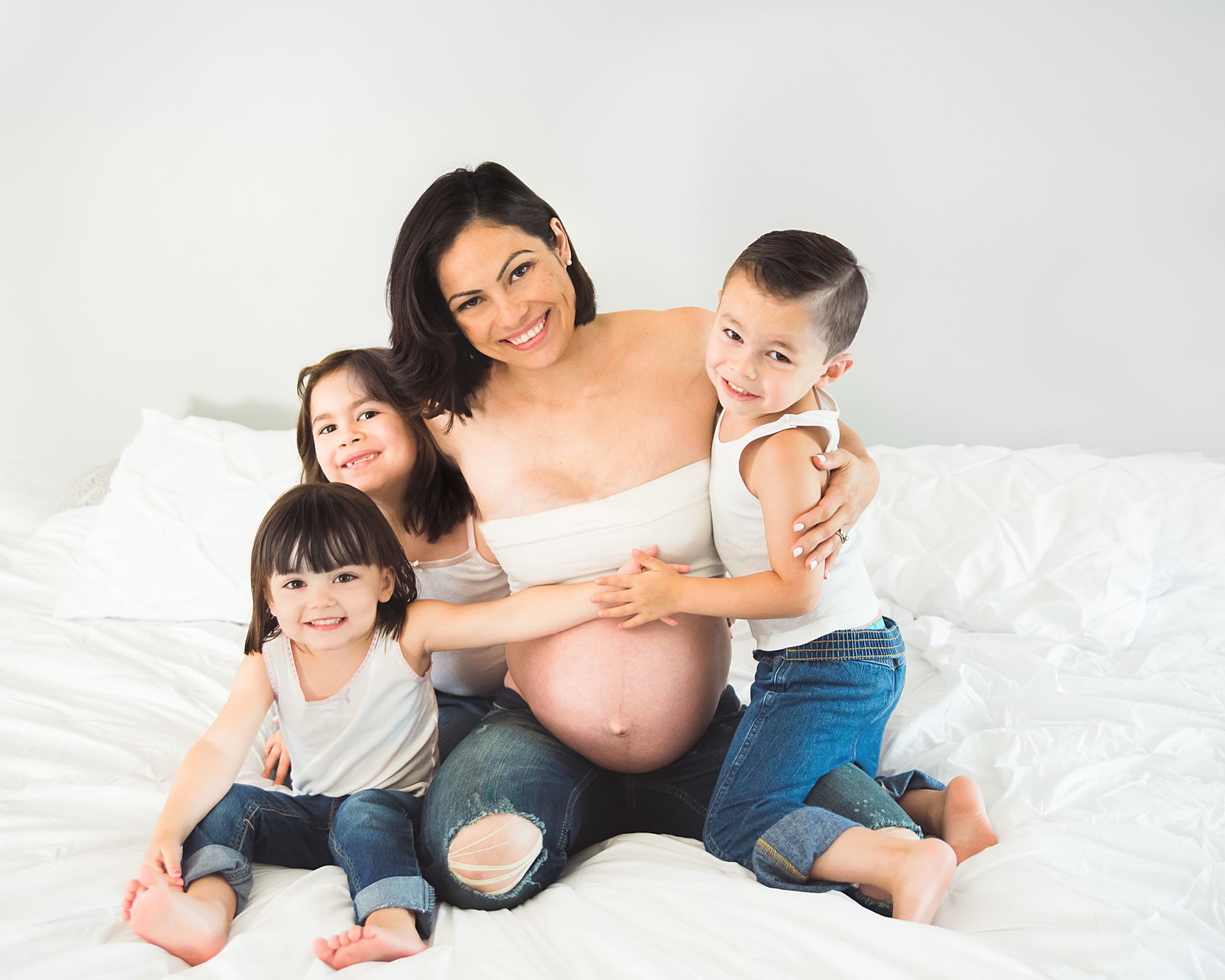 Mommy and me family maternity photo indoor session with three children wearing blue jeans and white shirts